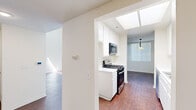 Located at 18418 Dearborn St in Northridge, CA, this 2-bedroom, 2-bathroom single-story residence offers a well-organized layout across a comfortable footprint. The living room is a standout space, featuring dramatically high ceilings, large clerestory windows that flood the room with natural light, rich hardwood-style flooring, and a wood-burning fireplace framed by a clean white mantle. Sliding glass doors open to an outdoor patio, further enhancing the sense of openness. Adjacent to the living room, the dining area continues the hardwood-style flooring and is highlighted by a decorative pendant light and a large window with vertical blinds. The galley-style kitchen is bright and functional, equipped with white cabinetry, a gas range, an over-the-range microwave, and a skylight that brings in abundant natural light. Both bedrooms are carpeted and well-sized, offering a quiet retreat, with the primary bedroom providing generous proportions and a closet. Each of the two bathrooms features white cabinetry, a large vanity mirror, and hardwood-style flooring. Hallways connect the rooms efficiently, and a dedicated closet adds practical storage to this thoughtfully designed Northridge residence.