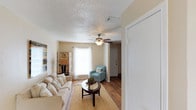 This two-floor residence offers a well-organized layout with consistent finishes and functional design throughout. The living room serves as a welcoming central space, featuring hardwood-style flooring, a textured ceiling, and a ceiling fan with integrated lighting. Natural light enters through a window fitted with blinds, and the room comfortably accommodates seating arrangements for relaxing or entertaining.

Adjacent to the living area, the dining space includes hardwood-style flooring and is illuminated by a pendant light fixture suspended from the ceiling. Vertical blinds cover a sliding door, allowing control over natural light.

The kitchen is configured in a galley layout, featuring warm wood-toned cabinetry, granite-style countertops, a double stainless steel sink, and black appliances including a full-size refrigerator. The flooring continues the hardwood-style aesthetic seen throughout the common areas.

The bedrooms are carpeted and each equipped with ceiling fans and natural light from windows. Walk-in closets with built-in shelving provide ample storage. One bedroom features a distinctive circular window as an accent detail.

The bathroom includes a tub-shower combination with a curtain, a granite-style vanity countertop, a framed mirror, and overhead lighting, completing a practical and cohesive interior.