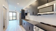 This 410 square foot apartment in Oakdale, MN, offers a modern and efficient living space. The single-floor layout maximizes functionality with a well-appointed kitchen, bathroom, and dedicated laundry area. The kitchen showcases sleek dark cabinetry contrasting with white subway tile backsplash and stainless steel appliances, including a refrigerator and range. Light-toned wood-look flooring flows throughout, enhancing the sense of space and continuity. The bathroom features a clean, minimalist design with a bathtub, toilet, and vanity. The laundry area is equipped with a stacked washer and dryer unit, optimizing space usage. Recessed lighting and a glass door in the kitchen area suggest attention to natural light. The overall design aesthetic is contemporary and cohesive, with a neutral color palette and streamlined fixtures. This apartment efficiently combines style and practicality in a compact urban living space.