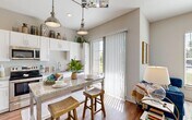 Located at 10945 Nuckols Road in Glen Allen, Virginia, this one-bedroom, one-bathroom residence offers a thoughtfully designed single-floor layout. The open-concept kitchen is a standout feature, boasting white shaker cabinetry, granite countertops, a subway tile backsplash, stainless steel appliances, and a center island with bar seating. Pendant lighting and a sliding glass door flood the space with natural light, leading to an outdoor access point. The kitchen flows seamlessly into the living room, which is anchored by a modern fireplace with a clean white surround and warm hardwood-style flooring. Large windows bring in additional natural light and offer views of the surrounding greenery. The bedroom provides a comfortable retreat with plush carpeting, a generous window, a dedicated closet, and direct access to the bathroom. The bathroom features a granite-topped vanity with white cabinetry and a glass-enclosed walk-in shower adorned with large-format marble-style tile. A bold teal entry door adds a distinctive architectural accent, while high ceilings throughout contribute to an airy, open ambiance. This residence combines practical functionality with modern design details.