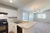 Located at 6710 Collins Road in Jacksonville, FL, this one-bedroom, one-bathroom residence offers a well-designed, single-floor layout that maximizes functionality and comfort. The open-concept main living area seamlessly integrates the dining room, kitchen, and living room into one cohesive space. The kitchen features white cabinetry, light stone-look countertops, a breakfast bar peninsula, and black appliances including a refrigerator, electric range, and dishwasher, all set atop warm wood-look flooring. A pendant light fixture above the peninsula adds a stylish touch. The living room is generously sized, finished with plush carpeting, a ceiling fan, and windows that invite natural light. The bedroom offers comfortable proportions with plush carpet, a ceiling fan, a closet, and access to natural light through a window. The bathroom is clean and functional, featuring a single-sink vanity with white cabinetry, stone-look countertop, a tub-shower combination, and wood-look flooring. Additional highlights include an in-unit laundry area, a hallway connecting the main spaces, and a private balcony with outdoor views — accessible via sliding glass door — ideal for enjoying the Florida climate.