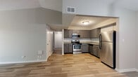 This single-floor residence offers a thoughtfully designed layout with modern finishes and a neutral color palette throughout. The kitchen is a standout feature, equipped with a full suite of stainless steel appliances including a refrigerator, electric range, microwave, and dishwasher. Gray cabinetry pairs with granite-look countertops and a classic white subway tile backsplash, creating a clean, contemporary aesthetic. The kitchen opens toward a dedicated dining area, accented by a stylish pendant light fixture.

The living area is generously proportioned, featuring wood-look plank flooring that extends throughout the main areas of the home. A sliding glass door with vertical blinds allows natural light to fill the space and provides access to the outdoors. The open layout between the living room, dining space, and kitchen promotes a connected, airy feel.

Bedrooms are carpeted for comfort and include closets with built-in shelving and hanging rods. The bathroom features a granite-topped vanity with gray cabinetry, brushed nickel hardware, and a round framed mirror, lending a refined touch. Textured ceilings and consistent gray-toned walls tie the overall design together, while a hallway connects the private areas of the home seamlessly.