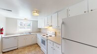 This two-floor townhome offers a straightforward, functional layout across multiple rooms designed for comfortable everyday living. The kitchen is outfitted with white cabinetry extending from base to ceiling, providing ample storage throughout. Light-toned laminate countertops offer generous prep space, while a white electric range, under-cabinet ventilation hood, and full-size refrigerator complete the appliance package. A tile backsplash lines the cooking area, and a window above the sink allows natural light to brighten the space. Tile flooring runs throughout the kitchen.

The living area is carpeted and features a large sliding glass door fitted with vertical blinds, opening to an outdoor view of greenery. The bedrooms are also carpeted, each featuring neutral wall tones and windows that bring in natural light and exterior views. The rooms are well-proportioned and versatile in their use.

Two bathrooms serve the townhome. One includes a tiled tub-and-shower combination with a marble-style vanity countertop and mirror. The second features a standalone shower with a frosted glass door and classic white subway tile wainscoting. Both bathrooms maintain a clean, utilitarian aesthetic consistent with the overall character of the home.