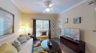 This single-floor, 2-bedroom, 2-bathroom residence offers a thoughtfully designed layout with consistent finishes and a welcoming ambiance throughout. The living room serves as the heart of the home, featuring crown molding, wood-style flooring, a ceiling fan with light kit, and large windows that invite natural light and views of surrounding greenery. A dedicated dining area sits adjacent to the living space, offering a cozy setting accented by warm lighting and framed wall art. The galley-style kitchen is well-equipped with ample white cabinetry, granite-style countertops, a full suite of white appliances, and a window that brings in additional natural light. Both bedrooms are generously sized and carpeted, providing a comfortable retreat. The primary bedroom features a row of high windows for natural light, while the second bedroom offers a serene, neutral aesthetic. Each bathroom is well-appointed — one features a dual-sink vanity with granite-style countertops and wood-style flooring, while the other includes a walk-in shower and extended vanity with storage. Crown molding and neutral warm tones unify the entire space, creating a cohesive and inviting atmosphere throughout.