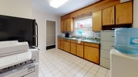 Located at 714 Riverside Dr in Salisbury, Maryland, this two-floor professional space, known as Oak Hill, offers a well-organized layout suitable for office or business use. The ground floor serves as the primary reception and work area, featuring neutral-toned carpeting with a subtle pattern, white chair-rail molding along the walls, and a central staircase with wood-and-metal railings leading to the upper level. This main area accommodates a large executive desk setup and provides a welcoming, open feel.

A private office off the main floor includes a workstation, a small sofa, and wall décor, creating a comfortable yet functional environment. The upper floor contains two additional rooms, each carpeted and lined with full-wall louvered closets offering generous storage. One room is configured as a private office with multiple windows overlooking surrounding greenery, while the second serves as a small conference room with a round table and seating. A full bathroom with tiled walls and a shower/tub combination is also present. The kitchen features warm wood cabinetry, green countertops, tile flooring, a window, and full appliances including a refrigerator and in-unit washer, rounding out the practical amenities of this versatile space.