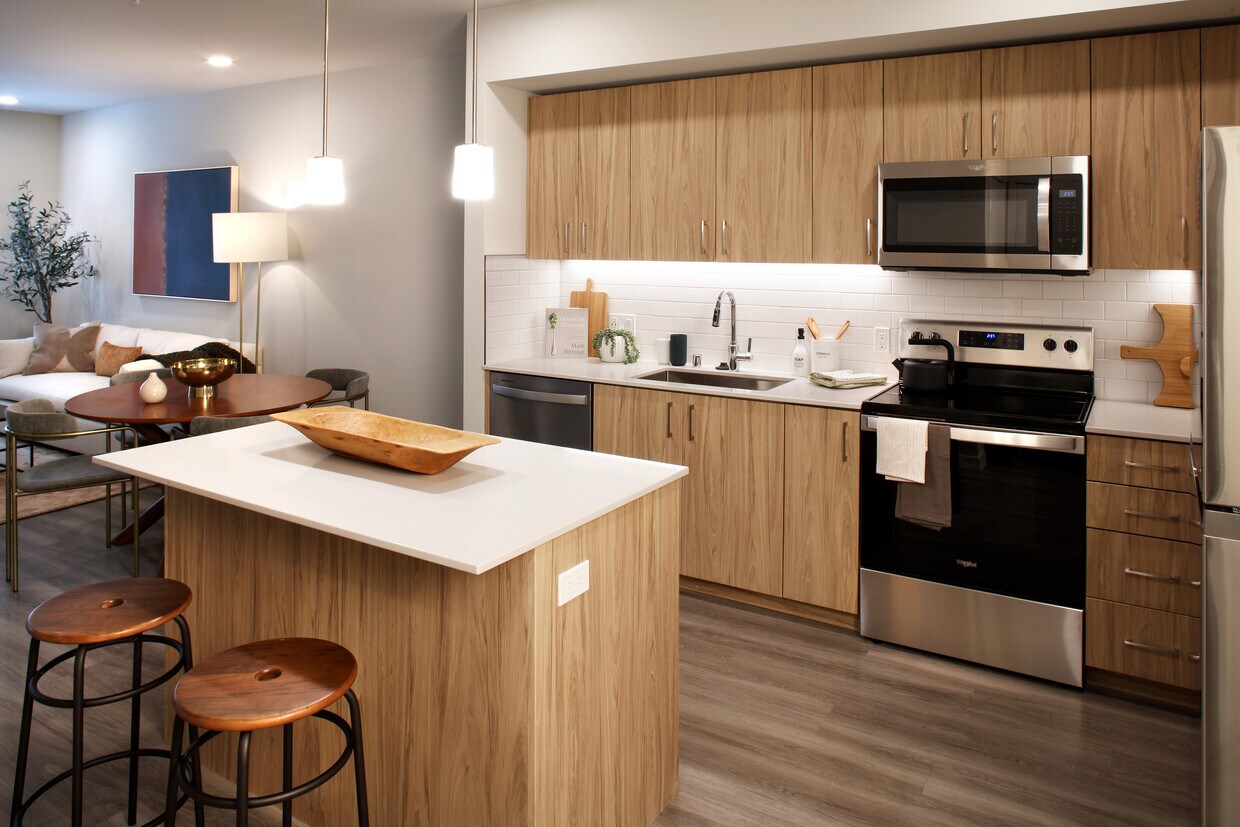 Cocina Design Collection II con gabinetes de roble, encimeras de cuarzo blanco y salpicadero de azulejos blancos - Avalon Alderwood Place
