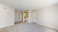 This efficiently designed one-bedroom, one-bathroom unit offers a practical and comfortable layout across a single floor. The living area features soft neutral-toned carpet, clean white baseboards, and light beige walls that create a warm, understated ambiance. Natural light flows through the space, with the main entry door opening into a combined living and entry area that transitions seamlessly toward the kitchen and bedroom.

The bedroom is generously proportioned, making it the largest area of the unit, and is finished with plush carpet. A sliding glass door leads to a private balcony, offering an outdoor view and allowing additional natural light to brighten the room. A dedicated closet provides practical storage within the bedroom.

The galley-style kitchen is thoughtfully arranged with white cabinetry, dark countertops, light wood-look flooring, and white appliances including a refrigerator, electric range, and over-the-range microwave. The layout maximizes efficiency within the compact footprint.

The bathroom is clean and functional, featuring a full tub and shower combination with white tile surround and wood-look flooring. Throughout the unit, the consistent use of neutral tones and clean finishes contributes to a bright, cohesive aesthetic well-suited for comfortable everyday living.
