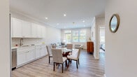 Located at 495 E Main St in Denville, NJ, this thoughtfully designed one-bedroom, one-bathroom residence offers a bright and efficient single-floor layout. The open-concept living, dining, and kitchen area forms the heart of the home, bathed in natural light from large windows that frame outdoor greenery. Crown molding and recessed lighting add a polished finish throughout.

The kitchen is well-appointed with white shaker-style cabinetry extending to the ceiling, stainless steel appliances including a refrigerator, range, microwave, and dishwasher, and clean white countertops. The dining area accommodates a round glass-top table, flowing seamlessly into the comfortable living room, which features a sliding glass door opening to a private balcony.

The bedroom offers a generous layout with a large window providing ample natural light and outdoor views, a built-in closet, and hardwood-style flooring that carries throughout the unit. A second closet provides additional storage. The full bathroom features white subway tile in the tub/shower surround, a white vanity, and neutral tile flooring.

Additional highlights include in-unit laundry, a hallway connecting all spaces efficiently, and a clean, contemporary aesthetic defined by a neutral palette and durable finishes throughout.