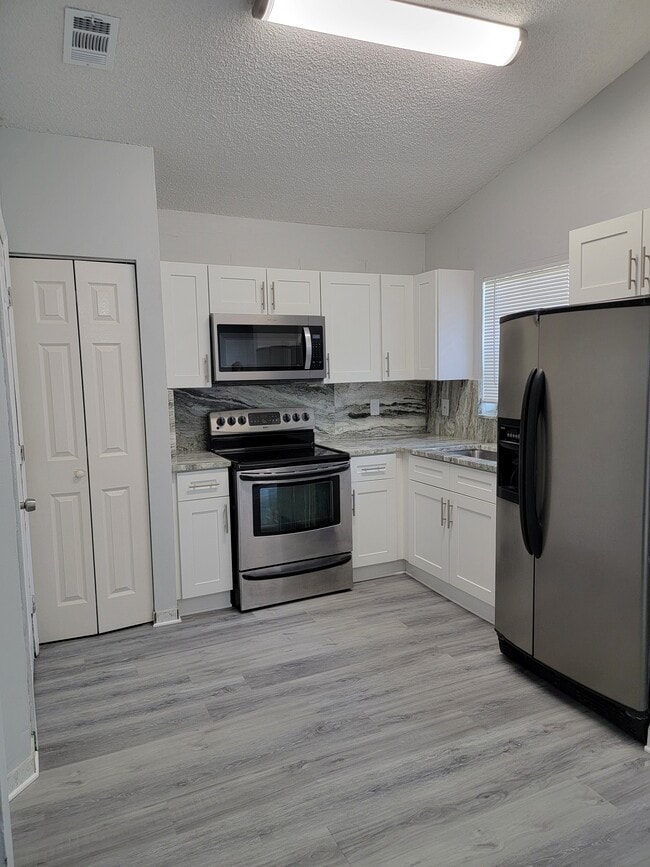 Cocina totalmente renovada con gabinetes nuevos, encimeras de granito y electrodomésticos de acero inoxidable. - 3621 NW 193rd St