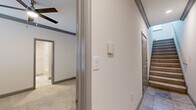 This thoughtfully designed multi-floor home offers four bedrooms, two bathrooms, and a two-car garage across three distinct levels. The ground floor houses a spacious two-car garage with automatic openers, providing generous vehicle and storage space. The main living level features an open living room with light wood-style flooring, crown molding, a ceiling fan, and a tile-surround fireplace flanked by windows that invite natural light. The kitchen is well-equipped with gray shaker-style cabinetry, white quartz countertops, a subway tile backsplash, stainless steel appliances including a double wall oven, built-in microwave, and a French door refrigerator, plus a central island for added workspace. The bathrooms are finished with tile flooring, a large vanity mirror, white quartz countertops, and a tub-shower combination with white tile surround. The bedrooms feature plush carpeting, crown molding, ceiling fans, and windows offering natural light — including one room with a distinctive arched window. Additional highlights include multiple hallways, closets, and staircases connecting the levels, ensuring a practical and efficient layout throughout this comfortable multi-story home.