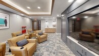 Located at 6822 Shannon Pky in Union City, GA, this thoughtfully designed screening and entertainment lounge offers a refined yet inviting atmosphere ideal for communal gatherings. The single-floor space is anchored by a striking tray ceiling with warm wood trim accents and recessed lighting, creating a layered, intimate ambiance reminiscent of a private cinema.

The living area is furnished with plush tan leather armchairs arranged in a theater-style configuration, each accompanied by sleek round side tables with built-in cup holders, ensuring comfort during extended viewing sessions. A large built-in media wall finished in a sophisticated slate-gray cabinetry anchors one side of the room, while a window on the opposite wall allows natural light to filter in.

A dedicated wet bar station lines one wall, featuring warm wood cabinetry, a white subway tile backsplash, a matte black faucet, and a clean white countertop — perfect for refreshments. Classic movie posters adorn the walls, adding a cinematic character to the space, while a vintage-style red popcorn machine serves as both a functional and decorative focal point.

The patterned carpet in soft blue and gray tones ties the design together, complementing the neutral gray walls and overall contemporary aesthetic of this well-appointed entertainment space.