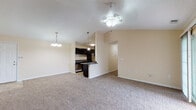 Located at 202 Pheasant Ave in Louisville, Kentucky, this single-story home offers a well-designed, open layout with a warm, neutral color palette throughout. The living and dining area is generously sized, featuring plush wall-to-wall carpeting, a ceiling fan with light fixture, and a decorative chandelier that adds a touch of elegance. Vaulted ceilings in the main living space create an airy, open feel, enhancing the sense of volume and comfort. The kitchen is thoughtfully appointed with dark espresso cabinetry, granite-style countertops, stainless steel appliances including a refrigerator, range, and built-in microwave, and tile flooring. A breakfast bar provides a convenient connection between the kitchen and living area. The bedrooms are carpeted and bathed in natural light through blinded windows, with one featuring a tray ceiling detail and ceiling fan. The primary suite includes a walk-in closet with built-in shelving and direct access to a private bathroom. An additional bathroom features a vanity with a large mirror and tile flooring. Throughout the home, textured ceilings, clean white trim, and consistent warm beige tones contribute to a cohesive and inviting atmosphere.