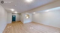 Located at 2504 NC-54 in Durham, NC, this single-floor unit offers a thoughtfully arranged layout that maximizes its compact footprint. Light hardwood-style flooring runs continuously throughout the space, creating a cohesive and clean aesthetic that brightens every area.

The spacious living room serves as the heart of the unit, featuring crisp white walls, a textured ceiling, and a wall-mounted HVAC unit for climate control. A window allows natural light to filter in, offering a pleasant view of the surrounding greenery and lending the room an airy, open feel. Ample wall space provides flexibility for a variety of furniture arrangements.

A pass-through opening connects the living area to the kitchen, which is outfitted with white cabinetry, under-cabinet lighting, and white appliances — including a dishwasher and range — delivering a clean, functional workspace. A dedicated closet provides practical storage to keep the living space organized.

The entry area, accessed through a distinctive teal door with a secure keypad lock, provides a welcoming transition into the unit. The overall design is neutral and move-in ready, with a bright, minimalist palette that suits a wide range of personal styles. This well-maintained unit combines efficient use of space with practical amenities in a convenient Durham location.