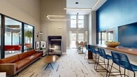 This 800 square foot office space in Little Rock, Arkansas, showcases a blend of modern design and functional workspace. The interior is characterized by soaring ceilings that create a sense of openness and grandeur. Large windows flood the area with natural light, offering views of the surrounding cityscape.

The space is divided into distinct zones, each serving a specific purpose. A standout feature is the striking geometric patterned wall, which adds visual interest and serves as a backdrop for a collaborative area. This space is furnished with sleek, grey workstations equipped with ergonomic chairs, ideal for focused work or small group discussions.

Adjacent to this is a spacious communal area centered around a large wooden table with vibrant blue chairs, perfect for team meetings or casual gatherings. The lounge area features a stylish orange leather sofa and a unique high-backed chair, providing comfortable seating for relaxation or informal conversations.

The office's design incorporates modern lighting solutions, including linear LED fixtures that add to the contemporary aesthetic while providing ample illumination. The flooring throughout is a distinctive distressed-look tile, adding character to the space.

A compact but well-equipped kitchenette area is tucked away, featuring glossy blue cabinetry and a white countertop. This space is stocked with essentials for employee convenience.

Overall, the office space successfully combines functionality with modern design elements, creating an environment that is both practical and visually appealing.