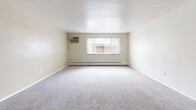 Located at 1033 N Downing St in Denver's Capitol Hill neighborhood, this single-floor, one-bedroom, one-bathroom unit offers a practical and efficient layout. The main living area is generously proportioned, featuring neutral-toned carpet, soft beige walls, and a large window that brings in natural light while offering views of the surrounding neighborhood. A wall-mounted air conditioning unit and baseboard heating system ensure year-round climate control.

The open-concept kitchen is separated from the living space by a wood-fronted peninsula, providing convenient counter seating or prep space. Wood cabinetry lines the kitchen walls, complemented by a ceiling fan overhead that promotes airflow throughout the common areas. A short hallway connects the living and kitchen area to the bedroom, closet, and bathroom.

The spacious bedroom features the same carpeted flooring and neutral palette, offering a calm and understated environment. The full bathroom includes a tub/shower combination with clean white surround, a toilet, and a vanity, maintaining the unit's simple and functional aesthetic throughout.

With its efficient use of space, practical amenities, and central Denver location, this unit suits those seeking straightforward, comfortable living in a well-connected urban setting.