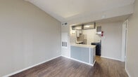 Located at 17710 Red Oak Dr in Houston, TX, this single-story residence offers a clean, functional layout designed for comfortable everyday living. The open-concept living area is finished with durable wood-look flooring and neutral-toned walls, creating a bright and welcoming atmosphere. A peninsula-style breakfast bar seamlessly connects the living space to the kitchen, which is equipped with stainless steel appliances including a refrigerator and an electric range with overhead ventilation. White cabinetry and under-cabinet lighting add both practicality and a modern touch to the cooking space. The bedroom features plush wall-to-wall carpeting that provides warmth underfoot, along with a ceiling fan with light fixture and a window dressed with horizontal blinds, allowing for natural light and ventilation. The bathroom includes a full-size tub and shower combination with white tile surround and chrome fixtures, maintaining a clean and classic aesthetic throughout. The unit also features visible HVAC vents and utility access panels, ensuring that essential systems are conveniently integrated into the space. Overall, the home presents a straightforward, well-maintained interior well-suited for practical, day-to-day living in the Houston area.
