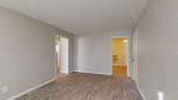 This single-floor residence offers a practical and comfortable layout with a neutral color palette of soft grays and warm beige tones throughout. The living areas are finished with durable wood-look flooring that flows seamlessly between rooms, creating a cohesive and easy-to-maintain surface. Natural light filters in through blinded windows, brightening the open, airy feel of the main spaces.

The kitchen is equipped with crisp white cabinetry, granite-patterned countertops, a stainless steel sink, and black appliances including a range and full-size refrigerator, all complemented by light tile-style flooring. A range hood provides practical ventilation above the electric stove.

The bedrooms are carpeted for comfort and each feature ceiling fans with integrated lighting. Closet space is provided, including a reach-in closet with shelving visible in one of the rooms. Baseboard heating units run beneath the windows in the carpeted rooms, ensuring warmth throughout. Multiple rooms offer direct views to adjoining spaces, supporting an interconnected and functional floor plan.

The bathroom includes a full tub-shower combination with white subway tile surround, a single vanity with white cabinetry, and a frosted window that allows natural light while maintaining privacy. Clean, simple finishes are consistent throughout the space.