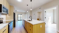 This well-appointed 2-bedroom, 1-bathroom residence at 101 Laurel Hill Rd in Brookfield, CT offers a thoughtfully designed single-floor layout with modern finishes throughout. Light oak hardwood flooring flows seamlessly across every room, creating a warm and cohesive aesthetic.

The heart of the home is an open-concept living, dining, and kitchen area. The kitchen stands out with a large central island topped with a white quartz countertop, warm-toned light wood cabinetry, a white subway tile backsplash, and stainless steel appliances including a refrigerator, range, and microwave. A matte black faucet and globe pendant lights add contemporary character. A sliding glass door connects the living area to an outdoor balcony, allowing ample natural light to fill the space.

Both bedrooms are comfortably sized — the primary bedroom offering generous square footage — each featuring neutral walls, large black-framed windows that invite abundant natural light, and double-door closets for practical storage. The hallway connecting the bedrooms to the main living area maintains the clean, open feel of the floor plan.

The bathroom is finished with large-format neutral tile flooring, a glass-enclosed walk-in shower with coordinating tile surround, warm wood vanity cabinetry, and matte black hardware accents. A dedicated laundry area and additional closets round out this efficient, modern residence.
