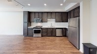 Located at 510 El Cerrito Plaza in El Cerrito, California, this single-floor residence offers a well-appointed and modern living experience. The open-concept layout seamlessly connects the living area and kitchen, creating a spacious, airy feel enhanced by warm wood-look flooring that flows throughout the main areas.

The kitchen is a standout feature, showcasing rich dark-wood cabinetry with sleek bar-pull hardware, crisp white quartz countertops, and a classic white subway tile backsplash. A full suite of stainless steel appliances — including a gas range, microwave, dishwasher, and refrigerator — completes this functional and stylish space. Recessed and track lighting provides excellent illumination throughout.

The generously sized living area is bathed in natural light, courtesy of multiple windows and a set of sliding glass doors that open to an outdoor balcony or patio, inviting the outside in. The clean, neutral wall tones provide a versatile backdrop for any décor style.

The bathroom is finished with light tile flooring, a full soaking tub with shower, built-in shelving, and a dark-wood vanity with a white basin sink, offering a clean and cohesive aesthetic that mirrors the rest of the home. Overall, this residence delivers a polished, contemporary design with practical amenities throughout.