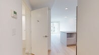 Located at 5670 Cambie St in Vancouver, BC, this thoughtfully designed one-bedroom, one-bathroom unit offers a clean, contemporary aesthetic throughout. Light hardwood flooring flows seamlessly across the open floor plan, enhancing the sense of space and continuity.

The open-concept kitchen is a standout feature, outfitted with flat-panel grey cabinetry extending to the ceiling, a soft blue glass tile backsplash, stone countertops, stainless steel appliances including a dishwasher and refrigerator, and an island with built-in shelving that doubles as additional workspace and storage. Recessed lighting keeps the kitchen bright and functional.

The living area benefits from large floor-to-ceiling windows that draw in generous natural light and provide views of the surrounding neighbourhood, creating an airy and inviting atmosphere.

The bedroom is a calm, minimalist retreat finished in crisp white tones with warm hardwood flooring and a full-width sliding door closet, offering practical storage in a compact space.

The bathroom is finished in all-white tile with a full soaker tub and shower surround, a recessed niche for toiletries, and a clean, modern aesthetic that complements the rest of the unit.

A hallway with in-unit laundry connections completes this efficiently planned and well-appointed home.