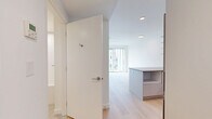 Located at 5670 Cambie St in Vancouver, BC, this thoughtfully designed one-bedroom, one-bathroom unit offers a clean, contemporary aesthetic throughout. Light hardwood flooring flows seamlessly across the open floor plan, enhancing the sense of space and continuity.

The open-concept kitchen is a standout feature, outfitted with flat-panel grey cabinetry extending to the ceiling, a soft blue glass tile backsplash, stone countertops, stainless steel appliances including a dishwasher and refrigerator, and an island with built-in shelving that doubles as additional workspace and storage. Recessed lighting keeps the kitchen bright and functional.

The living area benefits from large floor-to-ceiling windows that draw in generous natural light and provide views of the surrounding neighbourhood, creating an airy and inviting atmosphere.

The bedroom is a calm, minimalist retreat finished in crisp white tones with warm hardwood flooring and a full-width sliding door closet, offering practical storage in a compact space.

The bathroom is finished in all-white tile with a full soaker tub and shower surround, a recessed niche for toiletries, and a clean, modern aesthetic that complements the rest of the unit.

A hallway with in-unit laundry connections completes this efficiently planned and well-appointed home.