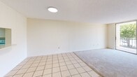 Located at 9060 NW 8th Street in Miami, FL, this two-bedroom, two-bathroom apartment is spread across two floors, offering a well-organized and functional layout. The main level features a combined kitchen and living room area, where light tile flooring extends through the kitchen into the living space, which transitions to carpet. The kitchen is equipped with white cabinetry featuring decorative trim, a full-size refrigerator, an electric range, and a drop-panel ceiling, providing a practical and self-contained cooking area. The living room is bright and open, with neutral walls and a seamless flow to the rest of the unit. A private balcony off the main level offers outdoor views of the surrounding greenery and neighborhood. The upper floor houses both bedrooms, each featuring soft carpeting, neutral tones, and natural light from large windows. The primary bedroom is generously sized and includes a double bi-fold closet with louvered doors. Both bathrooms are finished with warm earth-toned tile surrounds on the tub-shower combinations, tile flooring, and vanities with granite-style countertops. A dedicated hallway and additional closet space add to the unit's practical storage and circulation.