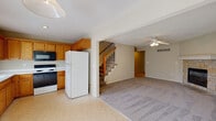 Located at 843 N Evergreen St in Gardner, Kansas, this two-story home offers a well-organized layout across two floors. The main level centers around an open living area with plush carpeting, a ceiling fan, and a corner stone-surround fireplace that serves as a notable focal point. Adjacent to the living area, the kitchen is outfitted with warm oak cabinetry, white laminate countertops, tile flooring, and standard appliances including an electric range, built-in microwave, dishwasher, and refrigerator. A window above the sink brings in natural light. A staircase with wooden balusters connects the main level to the upper floor. A half bathroom on the main level features tile flooring and an oak vanity. The attached garage provides concrete flooring and an automatic opener.

Upstairs, the carpeted bedrooms each include ceiling fans and closets. The primary bedroom connects to a private bathroom with a walk-in shower and oak vanity. Additional bedrooms are served by a full bathroom featuring a tub-shower combination with sliding glass doors, tile flooring, and matching oak cabinetry. Textured ceilings are present throughout the home.