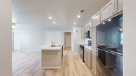 Located at 2330 Challenger Way in Watertown, South Dakota, this single-level 2-bedroom, 2-bathroom residence offers a clean, modern design with thoughtful finishes throughout. The kitchen serves as the heart of the home, showcasing a large center island with a light stone-patterned countertop and built-in sink, complemented by taupe shaker-style cabinetry, white countertops, and black appliances including a range, microwave, and refrigerator. Light-toned hardwood flooring runs throughout the main living and kitchen areas, enhancing the bright, open feel of the space. Both bedrooms are carpeted and feature windows with blinds that allow for natural light and outdoor views. The primary bedroom is generously sized with its own dedicated closet. Each of the two bathrooms features hardwood-style flooring, dark cabinetry with light countertops, and a full tub-shower combination. One bathroom includes direct access to a closet, adding practical functionality. Two closets throughout the home provide ample storage. Neutral gray-toned walls and recessed lighting throughout create a cohesive, contemporary ambiance that is both functional and inviting.