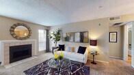 This single-floor residence offers a thoughtfully designed layout with distinct living, dining, sleeping, and bathroom spaces. The living room serves as the heart of the home, centered around a tile-surround fireplace flanked by large windows with blinds that invite natural light. Soft carpeting, neutral warm-toned walls, and a textured ceiling create a cozy yet refined atmosphere throughout the main living area.

The galley-style kitchen features dark espresso cabinetry, granite-look countertops, a double-basin sink, and black appliances including a refrigerator and range. It opens directly into a dedicated dining area illuminated by a pendant light fixture, with hardwood-style flooring providing a clean contrast to the carpeted living spaces.

The bedroom is generously proportioned, with plush carpeting, a ceiling fan with light kit, and full-width sliding glass doors providing access to a private balcony with outdoor views. Wall-mounted artwork and ample dresser space add to its functional comfort.

The bathroom is finished with hardwood-style flooring, a shower-tub combination, and neutral walls. Overall, the residence presents a balanced blend of functional design and comfortable living across its single floor.