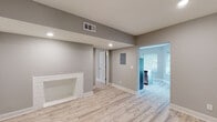 Located at 1207 E Armour Blvd, Unit 202 in Kansas City, Missouri, this renovated single-floor unit showcases a clean, modern aesthetic throughout. Light gray walls and light wood-tone luxury vinyl plank flooring flow seamlessly across the open living area, creating a bright and cohesive atmosphere. The living room features a decorative white brick fireplace surround, recessed lighting, and two entry doors, adding both character and practicality to the space. Natural light filters in through window blinds, enhancing the airy feel of the interior. An electrical panel is conveniently accessible within the main living area. The kitchen is well-appointed with gray shaker-style cabinetry, white quartz countertops, a classic subway tile backsplash, stainless steel appliances including a refrigerator, electric range, and over-the-range microwave, as well as a stainless steel sink. The open pass-through design connects the kitchen to the living area, supporting an efficient and welcoming layout. The bathroom offers a refined finish with a soaking tub and shower combo surrounded by large-format marble-look tile, a blue vanity with a white countertop, and coordinating tile flooring, delivering a spa-inspired feel. Overall, the unit presents a well-executed, move-in-ready space with updated finishes throughout.