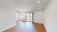 Located at 22035 Burbank Blvd in Los Angeles, CA, this one-bedroom, one-bathroom unit offers a well-organized, efficient layout across a single floor. Warm hardwood-style flooring flows consistently throughout the space, complementing the clean white walls and creating a cohesive, inviting atmosphere.

The open living room is bright and airy, featuring recessed lighting, a ceiling fan, and a sliding glass door that leads to a private balcony overlooking the surrounding neighborhood. The balcony provides an outdoor retreat with open views of the community and sky.

The galley-style kitchen is thoughtfully equipped with rich wood cabinetry offering ample storage, gray laminate countertops, a double basin sink, recessed lighting, and white appliances including a range and refrigerator.

The bedroom is a comfortable, well-lit retreat with a window that allows natural light to fill the room, continuing the warm flooring found throughout the unit. The white walls and simple ceiling fixture keep the space clean and versatile.

The bathroom features a combined tub and shower enclosed by a sliding frosted glass door with chrome hardware, paired with a white toilet, maintaining a clean and functional aesthetic throughout.