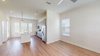 Located in Fort Worth, Texas, this two-story home offers a thoughtfully designed layout spread across two floors. The main level features an open-concept kitchen and living area anchored by warm hardwood-style flooring and abundant natural light streaming through multiple windows. The kitchen is equipped with gray shaker-style cabinetry, stainless steel appliances including a refrigerator, range, and microwave, white quartz countertops, and a center island with a sink and pendant lighting overhead — creating a functional and stylish space for cooking and entertaining. Hallways connect seamlessly to additional rooms and closets on the main floor. Upstairs, three carpeted bedrooms each feature ceiling fans and generous windows with outdoor views. The primary bedroom includes a walk-in closet and an en-suite bathroom. Bathrooms throughout the home are finished with gray vanity cabinetry, white countertops, and wood-style flooring, with the primary bath showcasing a soaking tub surrounded by elegant marble-style tile. Multiple closets provide ample storage throughout. The exterior features board-and-batten siding with a fenced backyard offering green lawn space for outdoor enjoyment.