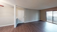 Located at 105 Cavalier Dr in Greenville, South Carolina, this single-floor residence offers a practical and comfortable layout with a variety of well-appointed spaces throughout. The living area features plush carpeting, neutral gray walls, and a ceiling fan, creating a relaxed and inviting atmosphere. A sliding glass door with vertical blinds allows abundant natural light to fill the room while providing access to the outdoors. The adjoining entryway transitions seamlessly between the carpeted living space and wood-look flooring that extends into the kitchen and bathroom areas. The kitchen is equipped with warm-toned wood cabinetry, granite-style countertops, a double-basin stainless steel sink, and a dishwasher, providing ample storage and functionality. The bathroom features a rich wood vanity with granite-style countertops, a large mirror with overhead lighting, and a full tub-shower combination with classic white tile surround and wood-look flooring. The bedrooms offer generous proportions, plush carpeting, and natural light from windows with blinds. One bedroom includes a spacious closet with bifold doors. Textured ceilings are consistent throughout the home, adding a traditional character to each room.