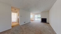 Located at 1056 Huntington Hill Dr in Manchester, MO, this single-floor, one-bedroom home offers a well-organized layout with a blend of carpet and hardwood-style flooring throughout. The living room serves as the centerpiece of the space, featuring a fireplace with a tile surround, a large sliding glass door that allows natural light to pour in and provides access to an outdoor balcony with views of mature trees. The textured ceiling and neutral white walls create a clean, bright atmosphere throughout. The galley-style kitchen is efficiently designed with warm wood cabinetry offering ample storage, laminate countertops, a stainless steel sink, and black appliances including an electric range and refrigerator. A closet at the end of the kitchen provides additional storage. The bedroom is generously sized with plush carpet, and features two windows on adjacent walls, filling the room with natural light and views of surrounding greenery. The bathroom includes a single vanity with a wood cabinet base and large mirror, a toilet, and a tub-shower combination with white tile surround. The overall layout is compact yet functional, making efficient use of every area within this single-level home.
