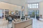 Located at 925 Battery Ave SE in Atlanta, Georgia, this single-floor communal space is designed with a sophisticated, contemporary aesthetic that blends functionality with refined style. The layout is open and expansive, anchored by soaring ceilings that amplify the sense of volume throughout the main area.

The central gathering zone features light-toned tile flooring and a prominent bar-height island topped with white quartz, illuminated by striking gold globe pendant lights. A bold black tile backsplash and open shelving add contrast, while a beverage station enhances the space's hospitality-forward character.

Adjacent to the main area, a lounge zone offers plush seating, a built-in media wall with dark shelving, a fireplace unit, and accent ottomans. Teal accent walls and curated artwork add bold pops of color. A private meeting nook features a built-in upholstered banquette with vertical channel detailing, a wood dining table, and navy velvet chairs, ideal for small gatherings or focused work sessions.

A game room enclosure with black-framed glass partitions houses additional bar seating and a billiards area. Throughout, varied flooring transitions—light tile and warm wood-look planks—define distinct functional zones. The cohesive design, layered lighting, and thoughtful furnishings create an inviting and polished communal environment.