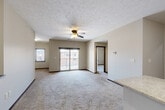Located at 8801 Executive Woods Dr in Lincoln, Nebraska, this two-story unit offers a well-organized layout across two levels. The ground floor provides direct access to an attached garage with a concrete floor, built-in storage shelving, and an automatic opener, connected to the main level via a carpeted staircase with a handrail.

The main living level is generously proportioned, featuring a bright, open living and dining area finished with plush carpet, a ceiling fan, and a textured ceiling. Sliding glass doors lead to a private balcony, allowing natural light to fill the space. The kitchen is positioned adjacent to the living area and includes granite countertops, providing a functional and attractive workspace.

The bedroom is a comfortable, carpeted room with ample wall space, served by a dedicated walk-in closet equipped with wire shelving on multiple walls for organized storage. The full bathroom features tile flooring, a granite-topped vanity with dark cabinetry, chrome fixtures, and a full tub-shower combination. A dedicated in-unit laundry room accommodates a full-size washer and dryer. A hallway connects the rooms efficiently, completing this practical and well-appointed two-story layout.