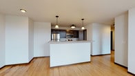 This single-floor residence is designed with an open-concept layout that seamlessly integrates the living and kitchen areas. The kitchen is well-appointed with dark espresso cabinetry, stainless steel appliances including a refrigerator, electric range, and microwave, along with light-toned countertops and a central island that doubles as a breakfast bar. Pendant lighting fixtures hang above the island, adding a warm, defined ambiance to the space. A pantry closet provides additional storage directly off the kitchen.

Light hardwood flooring runs consistently throughout the entire unit, lending warmth and visual continuity. The open living area is generously proportioned and benefits from natural light that filters in through multiple windows.

The bedrooms are bright and well-sized, each featuring ceiling fans, multiple windows with urban views, and sliding barn-style doors that open to organized closets with built-in shelving and hanging rods. The bathrooms include hardwood flooring, a shower-tub combination, vanity with dark cabinetry, and clean white fixtures. The floor plan also indicates a dedicated laundry area, adding everyday convenience to this well-configured space.