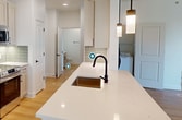 This contemporary 930 square foot apartment in Upper Kirby (#322) offers a harmonious blend of style and functionality. The open-concept design seamlessly integrates the living room and kitchen, creating a spacious feel. The kitchen is a highlight, boasting white cabinetry, stainless steel appliances, and a striking blue tile backsplash. A large island with a sink provides additional prep space and casual dining.

The bedroom, measuring 170 square feet, features large windows that flood the space with natural light and offer treetop views. A modern ceiling fan ensures comfort, while the hardwood floors add warmth and continuity throughout the apartment.

The bathroom showcases a clean, minimalist design with a marble-look shower surround and a vanity with ample storage. The apartment also includes a closet for additional storage needs.

Throughout the space, recessed lighting and pendant fixtures provide layered illumination. The cohesive use of light-toned walls and hardwood flooring creates a bright, airy atmosphere that maximizes the sense of space in this efficiently designed one-bedroom apartment.
