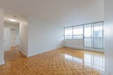 Located at 1900 Bloor St E in Mississauga, this well-laid-out two-bedroom, two-bathroom unit offers a comfortable and functional living space across a single floor. The interior is defined by warm, glossy parquet flooring that runs throughout the main living areas and bedrooms, adding a classic character to the space.

The living room is generously proportioned, featuring a wide wall of floor-to-ceiling sliding glass windows and doors that flood the room with natural light and provide direct access to the balcony. The city skyline views visible from multiple rooms lend the unit an elevated, airy feel.

Both bedrooms are well-sized, each featuring large windows with baseboard heating beneath them, ensuring comfort year-round while also framing the surrounding urban views. The primary bedroom offers a notably comfortable footprint with ample wall space.

The two bathrooms are cleanly finished with white cabinetry, granite-style countertops, integrated sinks, and large mirrors with overhead lighting. The main bathroom includes a tiled shower area. The kitchen connects conveniently to the living space, with tile flooring distinguishing it from the rest of the unit. Throughout, the unit maintains a bright, neutral palette with white walls and clean finishes, creating a move-in-ready environment.