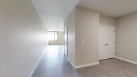 Located at 500 E 8th St, Unit 409 in Kansas City, MO, this modern one-bedroom, one-bathroom residence offers a well-designed layout with clean, contemporary finishes across a generously sized single floor. The open-concept kitchen and living area serves as the heart of the unit, featuring polished concrete floors, recessed lighting, and a sleek, functional kitchen outfitted with warm wood lower cabinets, crisp white upper cabinets, a classic white subway tile backsplash, and a full suite of stainless steel appliances including a range, microwave, dishwasher, and refrigerator. The spacious bedroom is finished with plush wall-to-wall carpeting and neutral tones, creating a calm and comfortable retreat. It connects directly to a dedicated walk-in closet equipped with dual wire shelving systems, offering substantial storage capacity. The bathroom is appointed with large-format gray tile flooring, a frameless glass walk-in shower with floor-to-ceiling vertical white tile, and a wood-toned vanity, delivering a refined, spa-like feel. Neutral warm-gray walls and clean white trim throughout the unit create a cohesive, modern aesthetic well-suited to urban living in Kansas City.