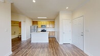 Located at 22541 Hickory Hill Square in Ashburn, Virginia, this single-floor residence offers a well-designed layout with a bright, open feel throughout. The kitchen serves as a functional centerpiece, featuring light wood cabinetry with built-in wine rack shelving, stainless steel appliances including a gas range, over-the-range microwave, and refrigerator, complemented by clean white countertops and a central island with a sink. Rich hardwood-style flooring extends through the main living areas, adding warmth and continuity. The living and dining areas are generously proportioned, featuring crown molding, ceiling fans, and multiple windows dressed with horizontal blinds that invite ample natural light and outdoor views of the surrounding greenery. A dedicated entry area with a glass-panel door further enhances the brightness of the space. The bedrooms are finished with soft carpeting and include well-sized closets with built-in shelving and hanging rods for organized storage. The bathroom is outfitted with a tiled tub-shower combination, wood-toned cabinetry, and a vanity with a mirror. Throughout the residence, neutral tones and clean finishes create a cohesive and move-in-ready atmosphere.