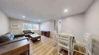 Located at 548 E Summit St in Kent, Ohio, this 2-bedroom, 1-bathroom unit offers a thoughtfully arranged single-floor layout that maximizes every inch of its compact footprint. The open-concept living and dining area is anchored by light wood-tone laminate flooring that runs throughout the space, creating a cohesive and clean aesthetic. Recessed lighting illuminates the living room, which features large windows that invite natural light and provide views of the surrounding neighborhood. A wall-mounted air conditioning unit and baseboard heating ensure year-round comfort. The kitchen is efficiently designed with white cabinetry, a marble-style countertop, a stainless steel sink, a dishwasher, and black appliances including an electric range and refrigerator. The primary bedroom offers a comfortable footprint with warm neutral walls and continued wood flooring, while the second bedroom provides additional flexible space. The full bathroom is finished with a marble-look vanity top, a white shaker-style cabinet, tile flooring, and a tub-shower combination with subway tile surround. Neutral gray tones throughout the unit lend a modern, move-in-ready feel to this well-maintained Kent residence.