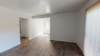 This single-floor residence offers a clean, modern aesthetic with a thoughtfully designed open layout. The main living and dining areas are finished with dark wood-style flooring that extends seamlessly throughout, lending warmth and visual continuity to the space. Large vertical-blind windows and a sliding glass door allow generous natural light to fill the rooms, creating a bright and airy atmosphere.

The kitchen is well-appointed with crisp white cabinetry, dark granite-style countertops, and a full suite of stainless steel appliances including a range, over-the-range microwave, and refrigerator. A window above the sink provides additional natural light, making the kitchen both functional and pleasant.

The bedrooms are finished with plush neutral carpeting and feature windows with vertical blinds, offering comfort and ample natural light. The rooms are generously proportioned with clean white walls, providing a versatile canvas for any interior style.

The bathroom includes a full tub and shower combination framed by white tile surround, a window for ventilation and light, and a dark-finished vanity with a white countertop. Throughout the home, consistent white walls, clean baseboards, and modern fixtures contribute to a fresh, move-in-ready presentation ideal for comfortable everyday living.