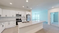 Located at 300 Commerce Ave in LaGrange, Georgia, this well-appointed 2-bedroom, 1-bathroom single-floor residence offers a thoughtfully designed open-concept layout. The kitchen serves as the heart of the home, showcasing crisp white shaker cabinetry, a subway tile backsplash, granite countertops, stainless steel appliances including a range, microwave, and refrigerator, and a generously sized center island with a built-in sink — seamlessly connecting to the bright, open living area. Light wood-style flooring runs throughout the main living spaces, while large windows invite abundant natural light. Both bedrooms are carpeted and include ceiling fans and ample closet space; the primary bedroom is notably spacious with multiple windows and access to a walk-in closet featuring built-in wire shelving. The bathroom is cleanly finished with granite countertops, a vessel sink, and a full walk-in shower enclosed by frameless glass doors and accented with white subway tile. Additional highlights include four closets, a dedicated laundry area, and a utility room, providing exceptional storage and functionality throughout. The overall aesthetic is clean, modern, and move-in ready.