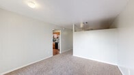 This single-floor unit offers a clean, functional layout designed for comfortable everyday living. The spacious living area is finished with plush neutral carpeting and crisp white walls, creating a bright and open atmosphere. A ceiling fan overhead adds practical comfort, while an open passageway connects the living space directly to the kitchen, promoting an easy flow between rooms.

The kitchen is well-appointed with warm wood-toned cabinetry, granite-style countertops, and stainless steel appliances including an electric range, over-the-range microwave, and refrigerator. Hardwood-style flooring runs throughout the kitchen, complementing the rich cabinetry tones. A window above the counter allows natural light to filter in, keeping the space feeling fresh and open.

The living area also features a sliding glass door that opens to a private balcony, providing outdoor access and views of the surrounding exterior. The entryway, framed by a classic paneled door, transitions smoothly from the balcony into the carpeted living space.

The bathroom is neatly finished with a full tub-and-shower combination clad in white tile surround, a wood-toned vanity with granite-style countertop, hardwood-style flooring, and a frosted window that brings in natural light while maintaining privacy. Overall, the unit presents a cohesive, move-in-ready aesthetic with practical finishes throughout.
