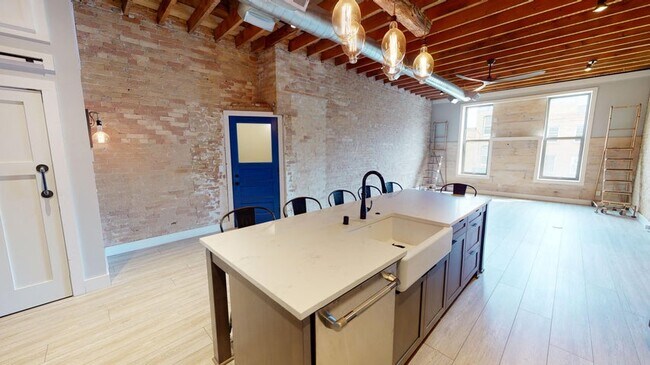 Kitchen 9' x 3' island with farmhouse sink that has ample storage, houses the dishwasher, and seats. - 334 Main St