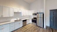 Located at 726 Fulton St in Chattanooga, TN, this single-floor unit showcases a thoughtfully designed open-concept layout with a clean, contemporary aesthetic. The living area immediately impresses with dramatically high ceilings and rich wood-look flooring that extends throughout the main living spaces, while a ceiling fan adds both function and style. Natural light filters in through well-positioned windows, creating a bright and welcoming atmosphere.

The kitchen is a standout feature, outfitted with crisp white shaker-style cabinetry, granite countertops, and a classic white subway tile backsplash. A full suite of stainless steel appliances — including a refrigerator, range, microwave, and dishwasher — completes this efficient and attractive culinary space.

The bedrooms offer a comfortable retreat, each featuring plush carpeting, high ceilings, and natural light from large windows with blinds. The primary bedroom connects directly to a private bathroom, providing added convenience.

The bathrooms are finished with granite-topped white vanities, wood-look flooring, and tiled tub-shower combinations framed by bold accent doors. A walk-in closet provides generous storage adjacent to the primary bath. The overall design strikes a balance between modern style and practical livability, making this Chattanooga residence a well-appointed and functional space.