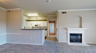This single-floor, 2-bedroom, 1-bathroom residence offers a practical and comfortable layout designed to maximize livability. The carpeted living room serves as the heart of the home, featuring a white-mantled fireplace with an elegant arched alcove above, crown molding, a ceiling fan with light fixture, and a sliding glass door that opens to a private balcony with outdoor views. The open-concept kitchen is accessible via a raised breakfast bar counter and is equipped with white cabinetry, gray countertops, a full-size refrigerator, a range, a microwave, and wood-look flooring that adds warmth to the space. A hallway connects the main living area to the two bedrooms and shared bathroom. The primary bedroom is a well-sized retreat featuring carpet flooring, a ceiling fan, and an arched window that brings in natural light. It is complemented by a dedicated walk-in closet outfitted with wire shelving systems for ample storage. The second bedroom is carpeted and offers a quiet, versatile space. The full bathroom includes a toilet, tub/shower combination, vanity with storage, and a mirror. Two hallways provide smooth circulation throughout the residence, completing this efficiently arranged and comfortable home.