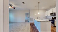 Located at 4000 Revere Blvd in Sherrills Ford, NC, this single-floor residence offers a well-designed, open-concept layout with modern finishes throughout. The kitchen serves as a central focal point, featuring white shaker cabinetry, granite countertops, a classic subway tile backsplash, and a full suite of stainless steel appliances including a refrigerator, electric range, and over-the-range microwave. A large center island with an undermount sink and elegant pendant lighting adds both functionality and style, flowing seamlessly into the main living area. The living room is accented with warm hardwood-style flooring, a ceiling fan, and French doors that open to a private balcony with natural views of the surrounding landscape. The bedrooms are carpeted for comfort, each equipped with ceiling fans and windows that allow natural light to filter in. The primary bathroom includes a dual-sink vanity with granite countertops, a subway-tiled walk-in shower, and tile flooring. A secondary bathroom mirrors the quality finishes with a subway-tiled tub-shower combination and granite vanity. An in-unit laundry area adds everyday convenience, completing this thoughtfully appointed single-level home.