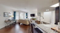 This thoughtfully designed one-bedroom, one-bathroom residence offers an efficient and stylish single-floor layout. The open-concept kitchen and living area serves as the heart of the home, where rich hardwood flooring flows throughout. The kitchen is outfitted with dark espresso cabinetry, stainless steel appliances, a tile backsplash, and a granite-topped breakfast bar with seating for two — ideal for casual dining or entertaining. A skylight above the kitchen adds an extra touch of natural brightness.

The living room is generously proportioned, featuring large windows and a glass door that invite abundant natural light and provide outdoor views. White walls and clean lines give the space a bright, modern feel.

The bedroom is a comfortable retreat, carpeted for warmth, and features a ceiling fan and a window overlooking greenery. It connects to a spacious walk-in closet with wire shelving and hanging rods offering ample storage.

The full bathroom is finished with large-format tile flooring, a dark vanity with granite countertop, a framed mirror, and a full-size tub-shower combination. A dedicated in-unit laundry area with shelving above completes this well-rounded residence, providing added convenience rarely found at this scale.